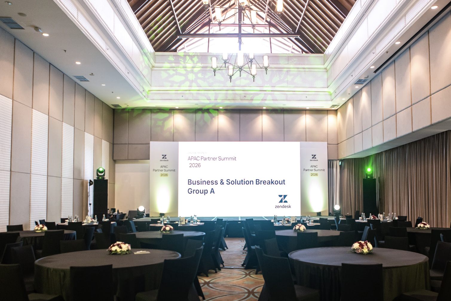A breakout room set and empty before a partner summit session, chandeliers above rows of seating