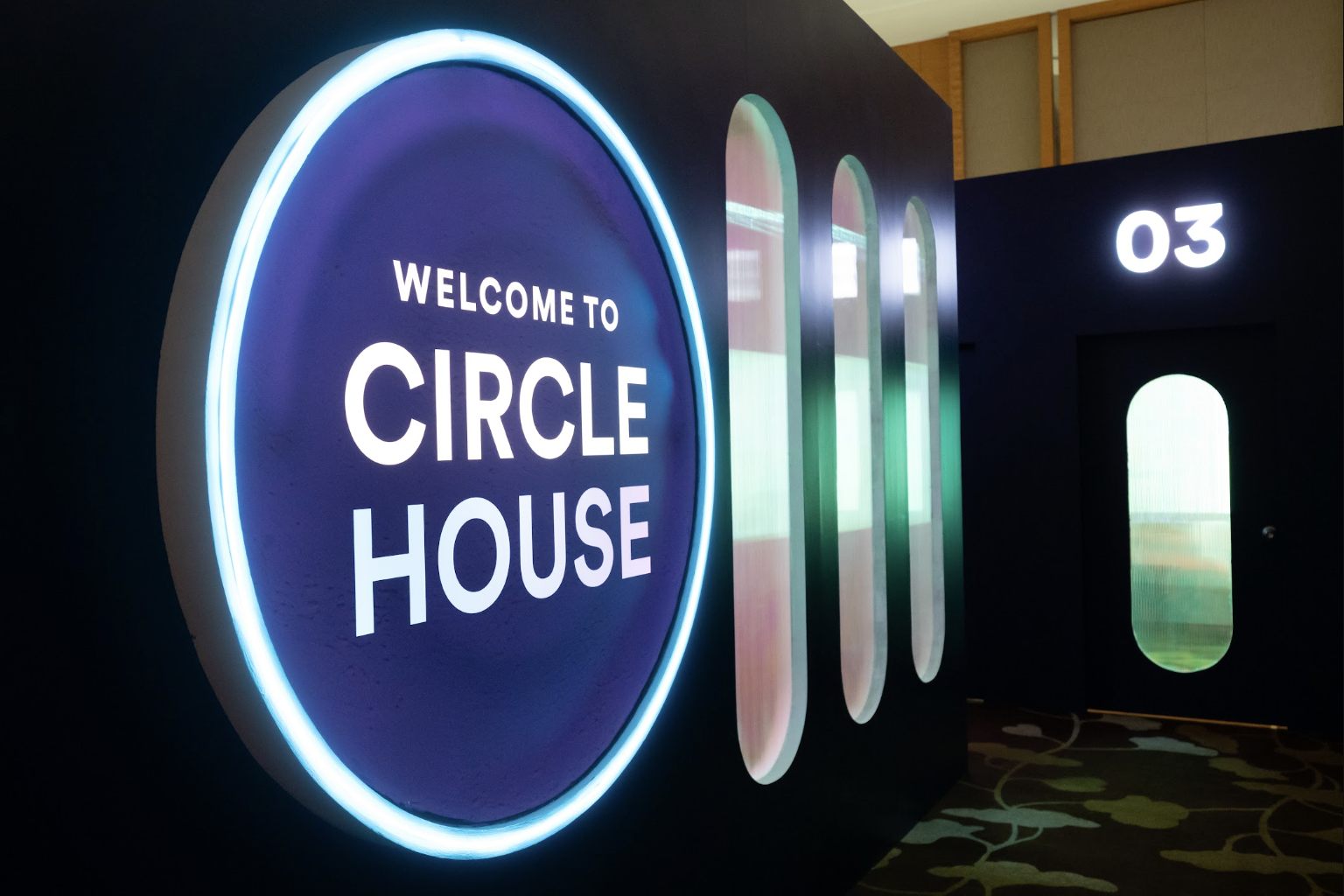 A neon-edged entrance disc set into a dark portal wall at a brand activation
