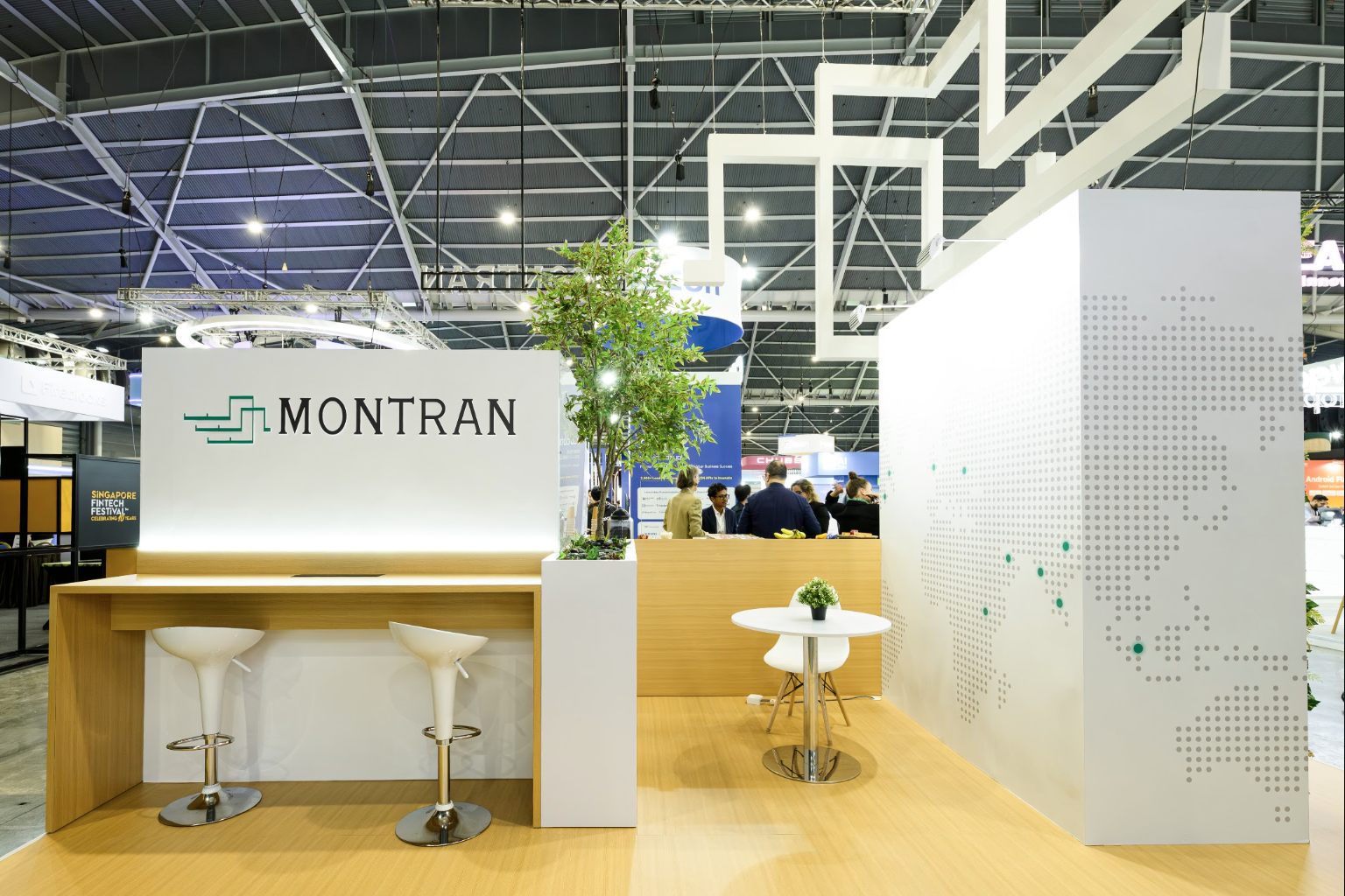 An exhibition stand in detail: timber counter, planting and a perforated world-map wall