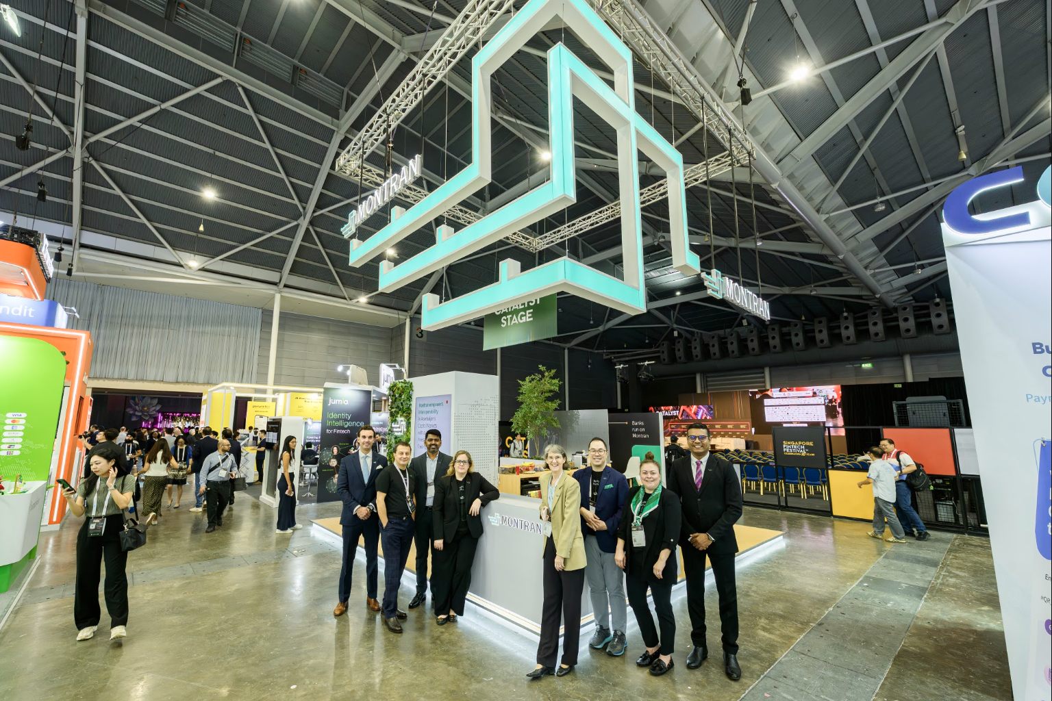 The Montran team beneath the stand's suspended identity structure on the festival floor