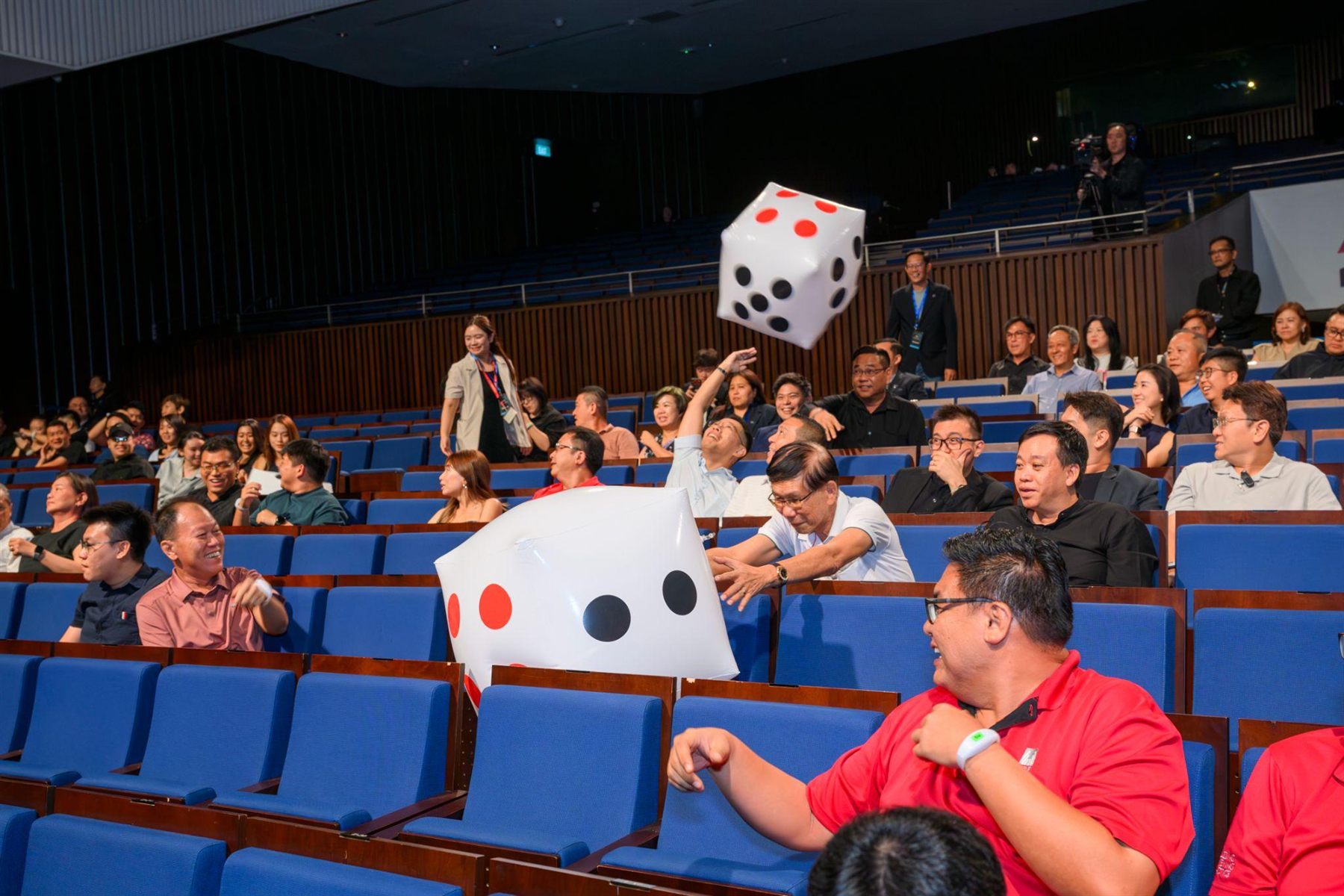 An audience interaction in the auditorium, oversized inflatable dice passing across the rows